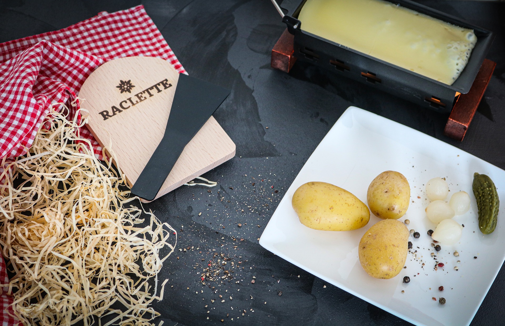 Raclette mit geschmolzenem Käse, Kartoffeln und Cornichons